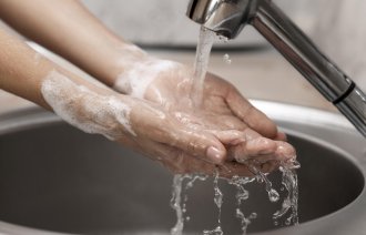 En person vasker hendene i rennende vann