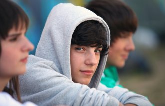 Bildet viser ansiktene til tre tenåringer som kikker ettertenksomt foran seg.