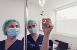 Bildet viser to sykepleiere som sjekker væske til en pasient.