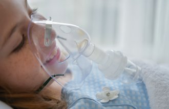 Bildet viser et barn med oksygenmaske foran ansiktet.