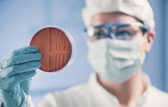 Bildet viser en forsker som holder en petriskål.