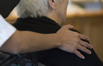 Eldre kvinne og sykepleier En sykepleier holder rundt en eldre kvinne