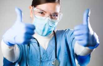 Bildet viser en sykepleier med tomlene opp