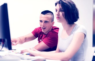 Bildet viser to studenter som sitter foran PC-en