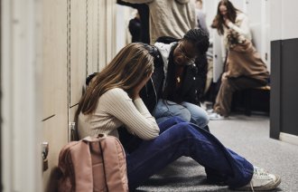 Bildet viser en skoleansatt som trøster en gråtende jente.