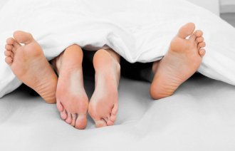 Bilde av nakne bein under en dyne