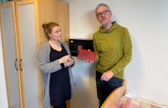 Bildet viser to personer, hvorav en viser frem en dosett.