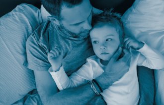 Bildet viser en far som sitter og holder et lite barn i armene