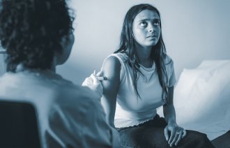 Bildet viser en sykepleier som setter en vaksinesprøyte i armen på en ung kvinne