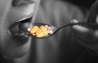 Bildet viser en mann som fører en skje med antibiotika mot munnen.