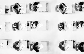 Bilde viser studenter som sitter ved pulter og har en eksamen. 