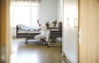 Bildet viser en sykepleier og en pasient som ser på mobilen sammen