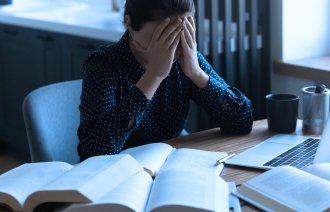 Bildet viser en student som hviler ansiktet i hendene.