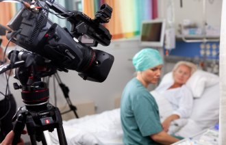 Bildet viser en anestesisykepleier som sitter på sengen med med en dukke som simulerer pasient