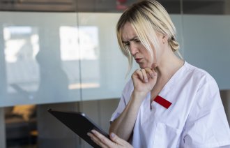 Bildet viser en kvinnelig sykepleier som bruker et nettbrett