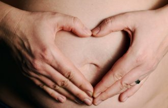 Gravid kvinne viser frem magen sin.