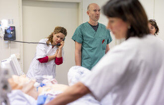 Bildet viser sykepleierstudenter og annet helsepersonell som simulerer pasientsituasjoner med bruk av en dokke.