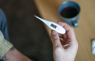 Bildet viser en person som holder et termometer