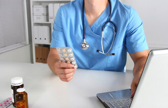 bildet viser en lege som holder et brett med piller i hånda