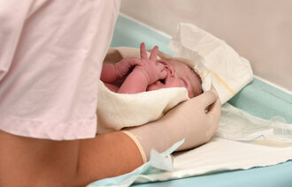 Bildet viser helsepersonell som holder i en nyfødt baby.