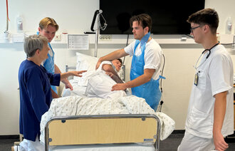 Bildet viser mannlige sykepleierstudenter som steller medstudent.