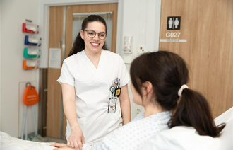 Bildet viser en sykepleier som kommer inn på et pasientrom