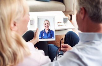 Bildet viser en sykepleier som har en digital videokonsultasjon med pasient og pårørende