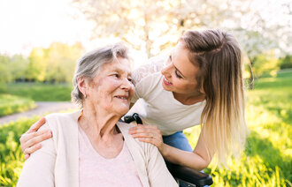 Bildet viser en eldre kvinne med demens som er på tur med en pårørende