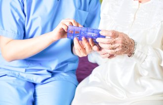 Bildet viser en sykepleier som viser en pasient en medisindosett