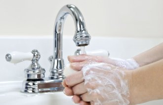 Bildet viser et par hender innsmurt av såpe, som vaskes i springen