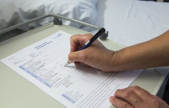 Bildet viser en hånd som fyller ut et PedSAFE-skjema