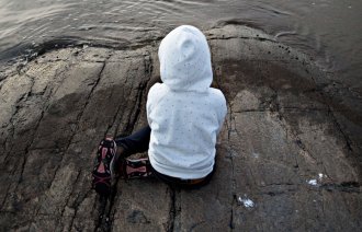 Bildet viser barn med ryggen til ved sjø