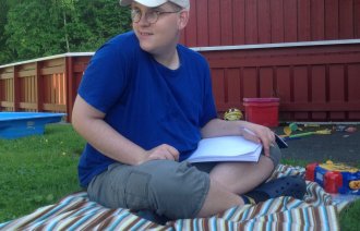 Bilde av Alexander som sitter på gresset med en bok i fanget Bilde av Alexander som sitter på gresset med en bok i fanget