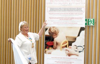 Bildet viser Aud Torild Bjerke som avduker et banner om barns rettigheter på sykehus.