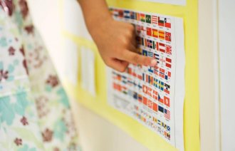 Bildet viser en kvinnehånd som peker på en plakat med ulike nasjonalflagg.