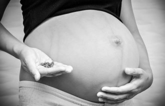 graviditet, legemidler Bildet viser en gravid mage og en hånd som holder mange piller.