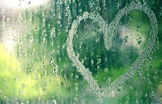 Bildet viser en vindusrute full av regndråper med et hjerte tegnet i regndråpene.