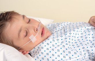 Bilde av gutt i sykehusseng med oksygenslange