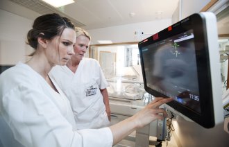 Bildet viser to sykepleiere som ser på monitoren på nyfødtintensiven.
