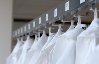 Bildet viser mange sykepleierantrekk som henger på rekke og rad.