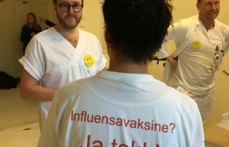 Bildet viser ryggen på en som har en t-skjorte med skriften Influensavaksine? Ja takk!