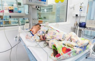 Bildet viser en baby med hjertefeil som ligger i kuvøse på sykehus