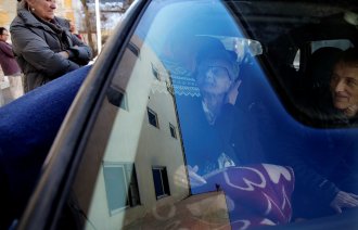 Bildet viser en eldre dame som sitter i en bil og som får klem av en yngre dame.