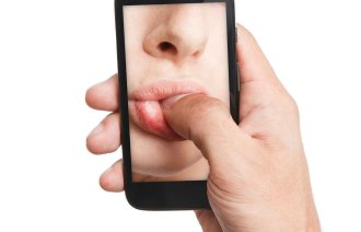 Lepper som suger på en tommel gjennom mobilen