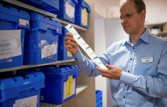 Apoteker Chris Jacobs ved Apotek 1 Asker holder opp en remse med multidoseposer. 