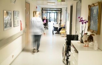 Sykepleier som går nedover en sykehjemskorridor