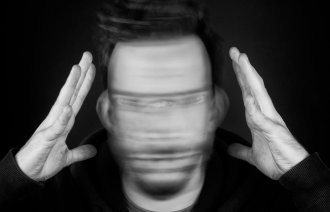 Mann som holder hendene opp og rister hodet fort fra side til side. 