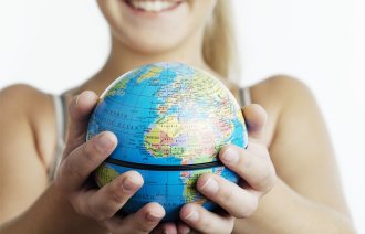 Bilde av en smilende kvinne som holder en jordklode mellom hendene