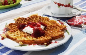 Bildet viser en vaffelplate med syltetøy og rømme.