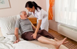 Illustrasjonsfoto av sykepleier som hjelper en pasient ut av senga